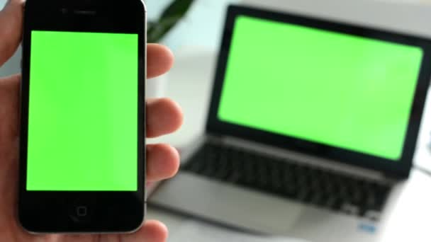 Смартфон з ноутбуком (зелений екран) фокус на смартфоні — стокове відео