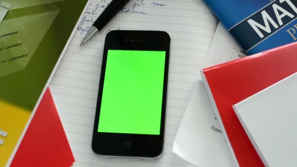 Смартфон (зеленый экран) с книгами, бумагой и ручкой — стоковое видео