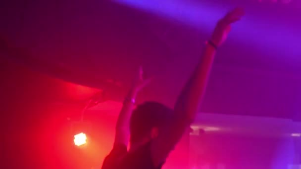 DJ играет на дискотеке, танцует с людьми на заднем плане — стоковое видео