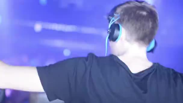 DJ joue à la discothèque, dansant en arrière-plan — Video