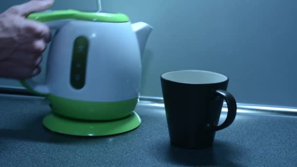 Encendiendo la tetera con la taza en el mostrador de la cocina — Vídeos de Stock