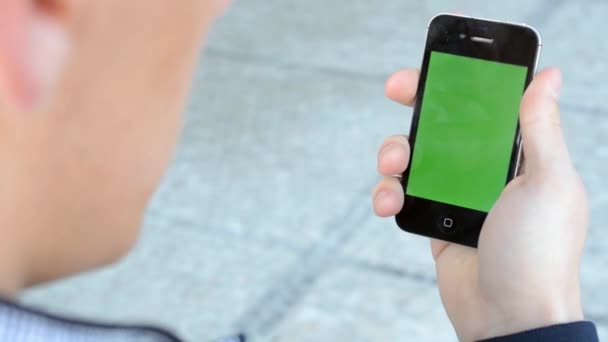 Een man kijkt naar de smartphone - groen scherm — Stockvideo