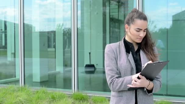 Mujer de negocios escribe al portapapeles (papel) antes de la construcción de negocios — Vídeos de Stock