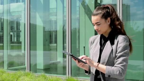 Mujer de negocios trabaja en tableta antes de la construcción de negocios — Vídeos de Stock