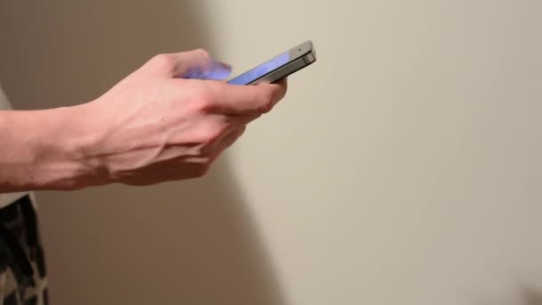 Hand (hombre joven) escribe en el teléfono inteligente - fondo blanco — Vídeo de stock