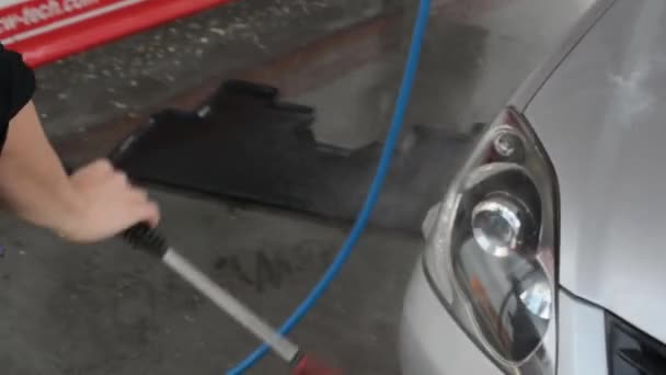 Man wassen auto met water (spray slang) — Stockvideo