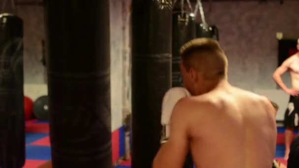 Homens praticam esporte - esportes de combate (boxe no saco) - no ginásio — Vídeo de Stock