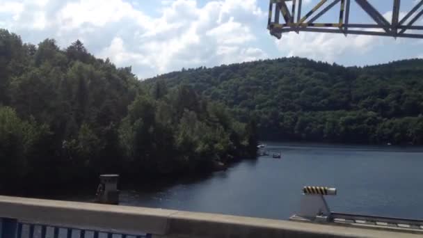 Швидка їзда через міст озеро з лісом на задньому плані — стокове відео
