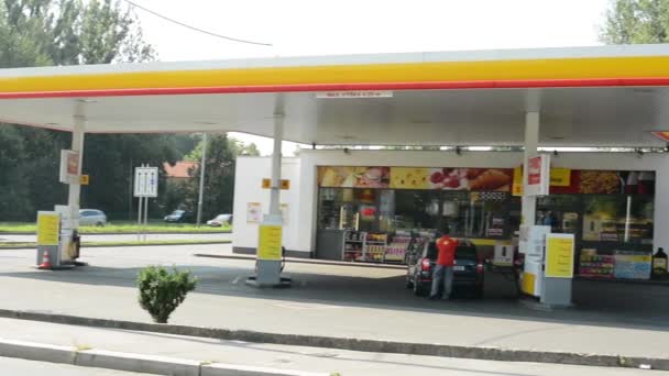 Posto de gasolina (bomba de óleo) Shell na cidade - com carros e pessoas . — Vídeo de Stock