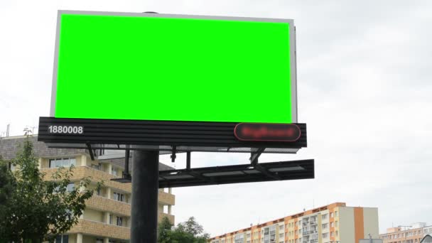 Panneau d'affichage dans la ville près de la route - écran vert - bâtiments avec des arbres en arrière-plan — Video