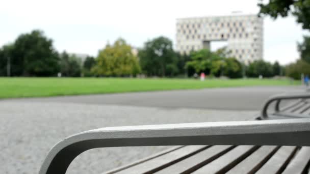 Park (grass, trees) - benches in row - modern building and people — Stock Video