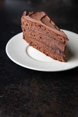 Bir parça çikolatalı kek kakaolu kek, çikolatalı ganache, kahverengi kremalı tatlı hazır sofrada atıştırmaya hazır uzay yemeği arka planında kırsal. en üstteki görünüm