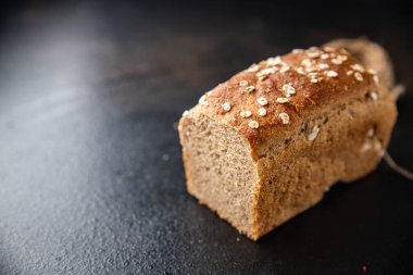 Yulaf ekmeği kepekli buğday, maya yok. Masada atıştırmalık bir şeyler var. Fotokopi masası arka planında.