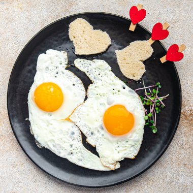 valentines day fried egg breakfast on the table scrambled eggs heart shape holiday decoration love date copy space food background