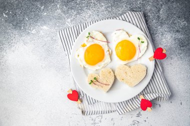 valentines day fried egg breakfast on the table scrambled eggs heart shape holiday decoration love date copy space food background