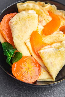 crepe persimmon thin pancakes fruit breakfast sweet dessert healthy meal food snack on the table copy space food background rustic top view