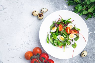 Paskalya salatası bıldırcın yumurtası bayram atıştırmalığı domates, marul karışımı masada sağlıklı yemek artıkları fotokopi uzayı arka plan kırsal manzarası 