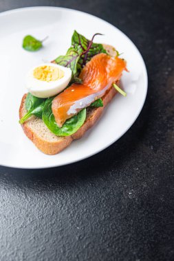 Sandviç somonu smorrebrod yumurtası, yeşil salata karışımı, tahıl ekmekli tost deniz ürünleri açık porsiyon yemek atıştırmalığı masa fotokopisi uzay yiyecek arka planında. 