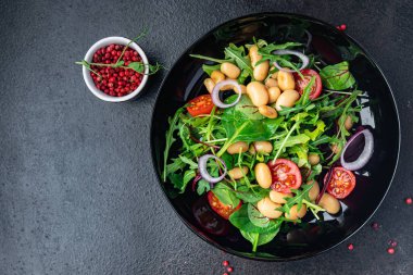 Fasulye salatası, domates, soğan, marul, taze sebze diyeti aperatifleri masanın üzerinde. Fotokopi uzayı yemek arka planı vejetaryen veya vejetaryen yemekleri.