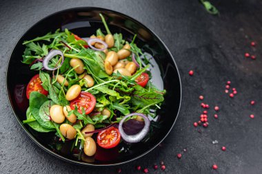 Fasulye salatası, domates, soğan, marul, taze sebze diyeti aperatifleri masanın üzerinde. Fotokopi uzayı yemek arka planı vejetaryen veya vejetaryen yemekleri.