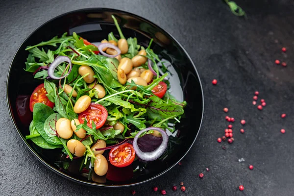 Fasulye salatası, domates, soğan, marul, taze sebze diyeti aperatifleri masanın üzerinde. Fotokopi uzayı yemek arka planı vejetaryen veya vejetaryen yemekleri.