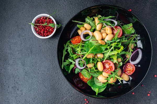 Fasulye salatası, domates, soğan, marul, taze sebze diyeti aperatifleri masanın üzerinde. Fotokopi uzayı yemek arka planı vejetaryen veya vejetaryen yemekleri.