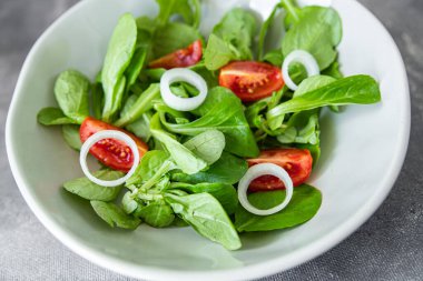 Sebze salatası domates, soğan, marul karışımı, mache yeşil sağlıklı yemek aperatifi masanın üzerinde fotokopi uzayı arka plan, kırsal üst görüş keto veya paleo diyet vejetaryen veya vejetaryen yemeği.
