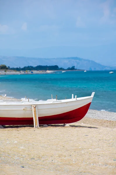 Красно-белая лодка на берегу — стоковое фото