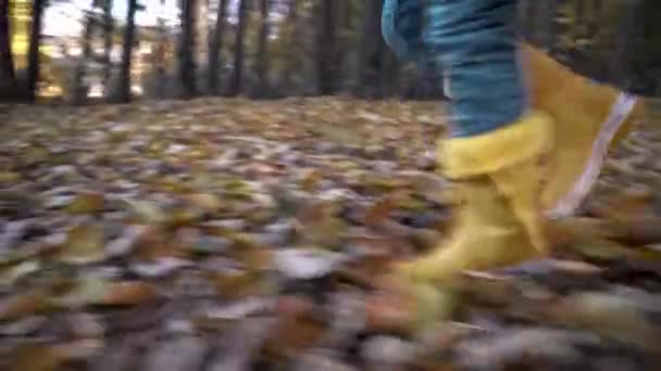 Het Kind Loopt Gele Rubberen Laarzen Jeans Droge Herfstbladeren Camera — Stockvideo