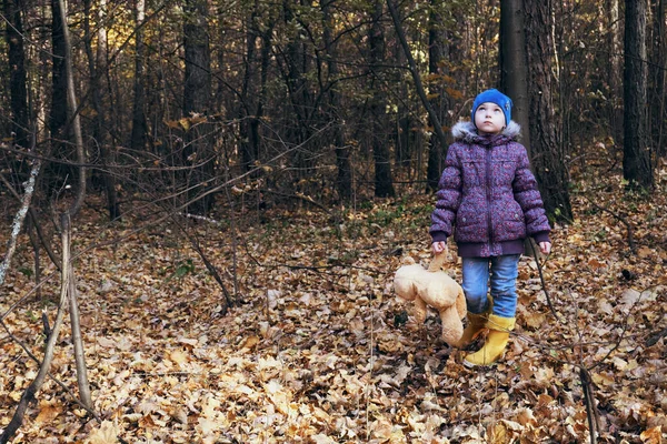 一个穿着亮黄色靴子的孩子站在那里 手里拿着一只泰迪熊的爪子 最好的朋友 呼吸清新的散步 — 图库照片