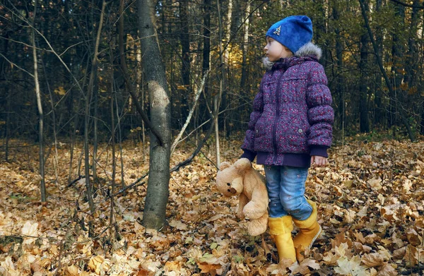 一个穿着亮黄色靴子的孩子站在那里 手里拿着一只泰迪熊的爪子 最好的朋友 呼吸清新的散步 — 图库照片