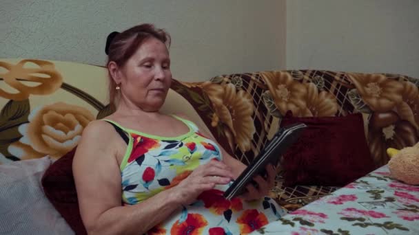 Uma Mulher Adulta Senta Sofá Olha Para Tablet Utilização Tecnologia — Vídeo de Stock