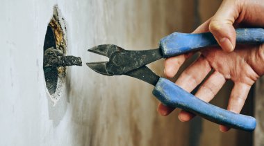 El, delikten keskinleşen yalıtılmış bir kabloya uzanan penseyi tutuyor. Kablolar, elektrik tesisatı, güvenlik, onarım ve inşaat.