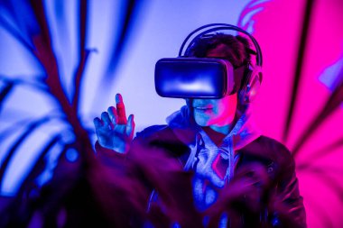 Sanal gerçeklikte VR gözlükleriyle etkileşime giren kadın, metaevrenin tadını çıkarıyor..
