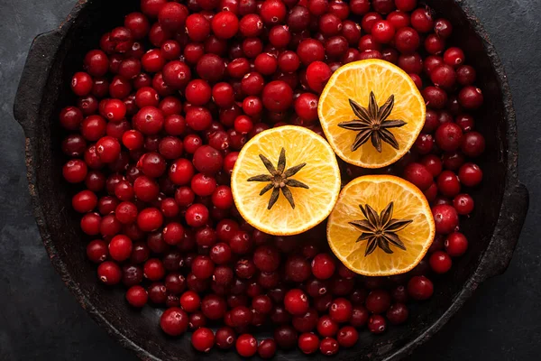 Świąteczne grzane składniki wina. Lingonberry, żurawina, czerwone jagody, anyż, cynamon, pomarańcza na ciemnym tle. Zdjęcie przytulnych wakacji w domu. Widok z góry. — Zdjęcie stockowe