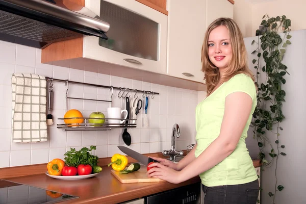 Young woman cuts fresh vegetables at the kitchen — Stock Photo, Image