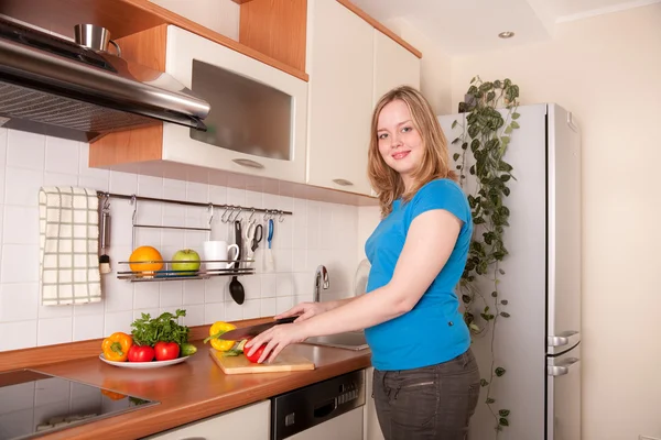 Mujer joven corta verduras frescas en la cocina —  Fotos de Stock