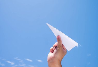 Gökyüzüne kağıt uçak fırlatmak, insanların eli mavi gökyüzü arka planına karşı kağıt zanaat tutmak.