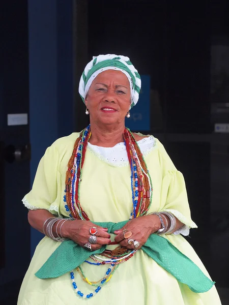 SALVADOR, BRASIL - 01 DE AGOSTO: Mujer brasileña vestida con ropa tradicional de Bahía anima a los turistas a ingresar al Museo Baianas en Salvador, Brasil, el 01 de agosto de 2012 —  Fotos de Stock