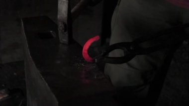 Demirci bir at nalı döver, kırmızı bir at nalı, kırmızı bir at nalı, çekiçle örse vurur.