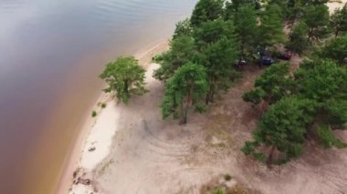 Kumlu sahil, göller, denizler, nehirler, kumlu sahildeki yeşil yemyeşil yemyeşil ağaçlar, açık hava eğlencesi, bulutlu bir gün, ağaçlar arasındaki arabalar, drone atışları.