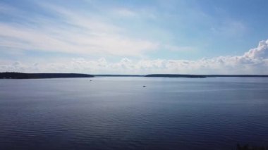 Göl, nehir, deniz, ağaçların tam üstünden çekiliyor, uzaklarda küçük bir tekne yüzüyor, aydınlık bir gün, gökyüzü mavi, hafif obez