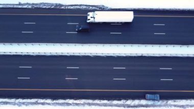 İHA 'nın yol boyunca pürüzsüz kalkışı, otoyol boyunca giden arabalar, kış, ağaçlarda ve yol kenarında uzanan kar, akşam, gün batımı, güneşten parlayan leylak.