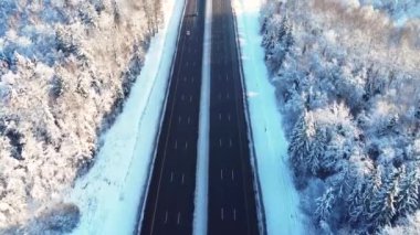 İHA 'nın yol boyunca pürüzsüz uçuşu, otoyol boyunca giden arabalar, kameranın tepeden tırnağa pürüzsüz yükselişi, kış, ağaçlarda ve yolun kenarında uzanan kar, akşam, gün batımı, mavimsi gölgeler.