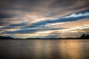 Constance Gölü 'nde gün batımı Güçlü sağanak ve güneş ışınlarıyla