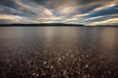Günbatımındaki taşlar Constance Gölü 'nde. Arka planda güçlü bulutlar var.