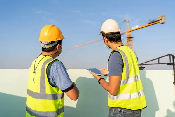 建設現場における建設クレーンの位置を検査監督するためにフォアマンを導入するタブレットを使用してエンジニア — ストック写真