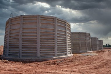 Su arıtma ve atık su arıtımı için bitmemiş beton boruların inşaatı. Sanayi arazisinin şantiyesinde çalışıyorlar. Endüstri araçları.