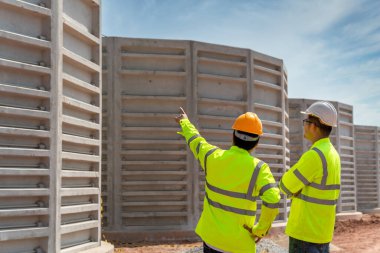 Mühendis ve inşaat işçisi, sanayi bölgesinde su arıtma ve atık su arıtımı için tamamlanmamış beton borular inşa etmeyi planlıyor. 