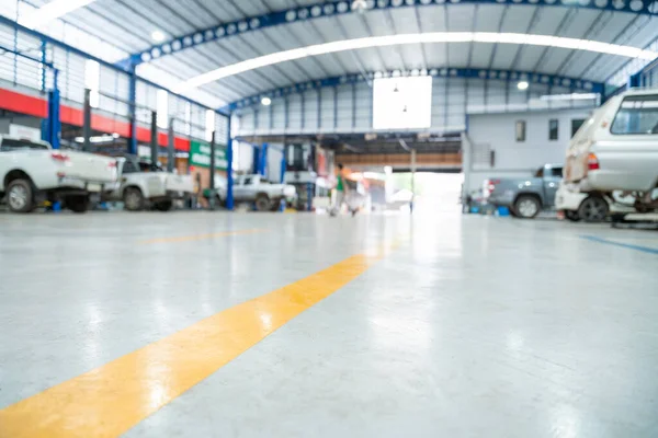 Blurred background of Car repair station paved with epoxy floor and electric lift for a car that comes to change the engine oil in the background of Car repair center with epoxy floors.